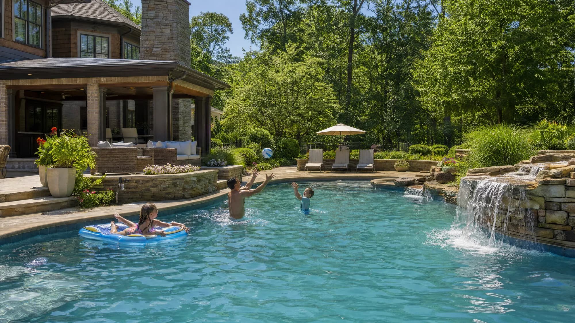 Family playing with a beach ball in the pool